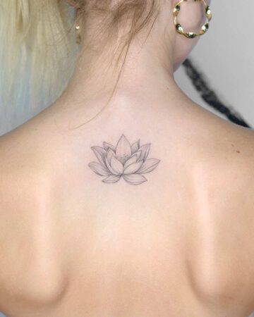 Delicate lotus flower tattoo on a woman's upper back, showcasing fine line work and intricate petal detail. The tattoo is a popular choice for back tattoo ideas. Done by tattoo artists in our fine line tattoo studio parlour shop Canggu, Bali