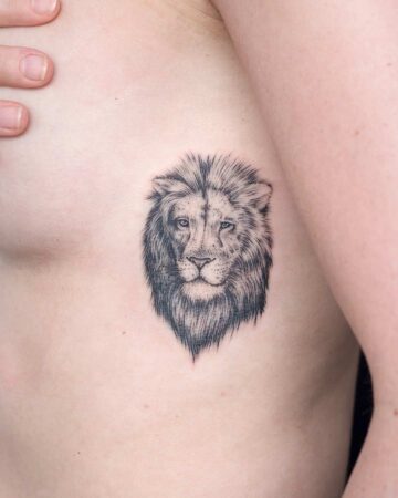 Detailed black and grey lion head tattoo on a person's chest, featuring fine line work. A striking chest tattoo design. Done by tattoo artists in our fine line tattoo studio parlour shop Canggu, Bali