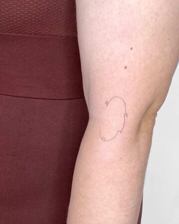 Fine-line minimalist tattoo of a flowing abstract shape on an arm, showcasing the delicate artistry of a small tattoo. This arm tattoo is a great example of minimalist tattoos. done by artists in our fine line tattoo studio Canguu Bali