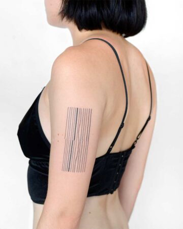 Geometric line tattoo on woman's upper arm in black top Done by tattoo artists in our fine line tattoo studio parlour shop Canggu, Bali