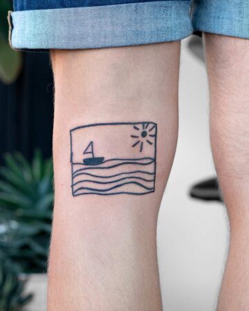 Minimalist boat tattoo on a leg, featuring a sailboat on wavy water under a sun, perfect for summer tattoo inspiration. Done by tattoo artists in our fine line tattoo studio parlour shop Canggu, Bali