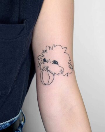 Minimalist line art dog tattoo on an arm, featuring a fluffy head and a ball in its mouth. A simple, elegant design. Done by tattoo artists in our fine line tattoo studio parlour shop Canggu, Bali