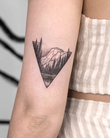 Minimalist nature tattoo design featuring a mountain range and forest scene inside a triangle, a stylish nature tattoo for the arm. Done by tattoo artists in our fine line tattoo studio parlour shop Canggu, Bali