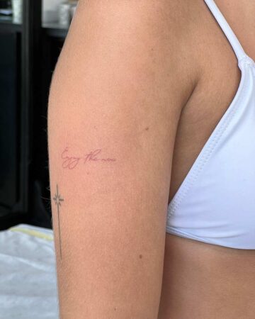 tattoo script lettering on the hand fineline fineline red color enjoy the now