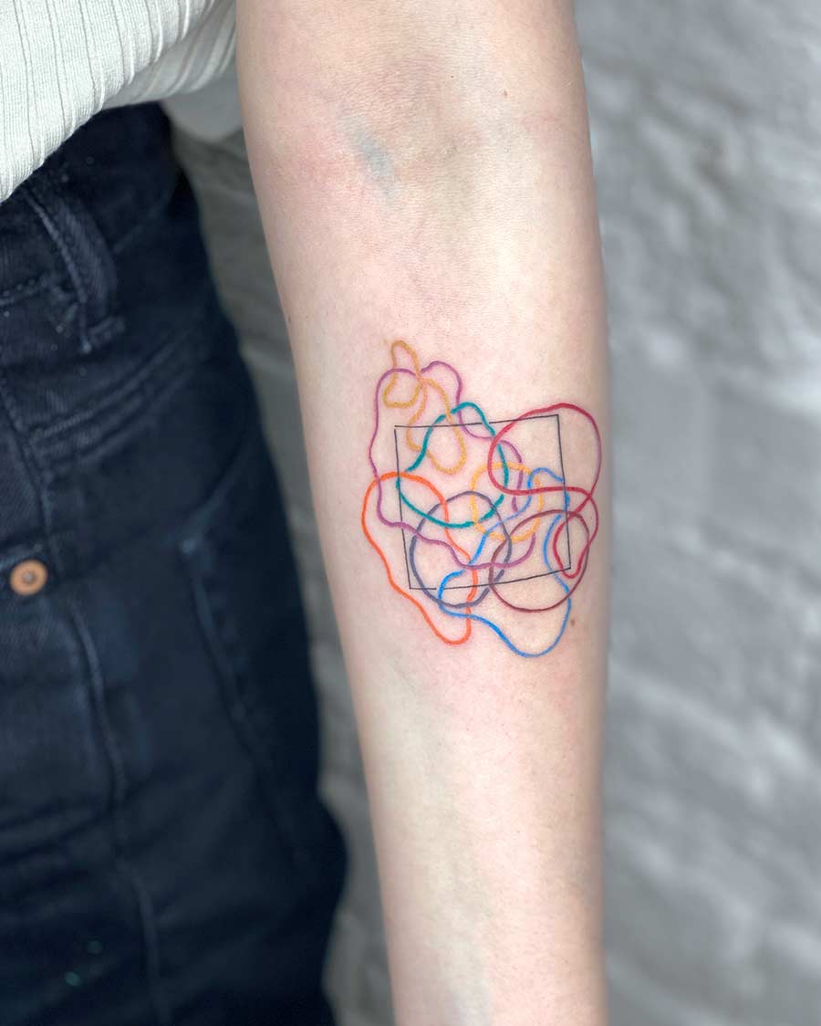 Colorful abstract tattoo design on an arm featuring intertwined lines in various bright hues, with a black square in the center. The tattoo gives an artistic and modern look. Done by tattoo artists in our fine line tattoo studio parlour shop Canggu, Bali