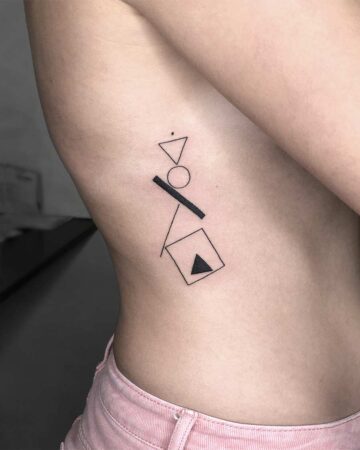 Minimalist geometric tattoo on a ribcage, featuring a triangle, circle, square, and diagonal line. The small, black ink design is a modern example of a minimalist tattoo, perfect for geometric tattoo inspiration. Done by tattoo artists in our fine line tattoo studio parlour shop Canggu, Bali