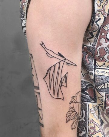 Abstract line tattoo of a woman's face on upper arm with patterned shirt Done by tattoo artists in our fine line tattoo studio parlour shop Canggu, Bali