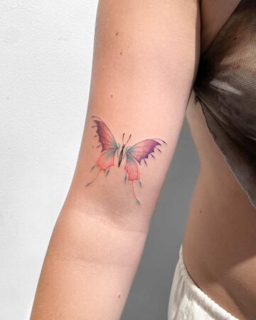 Colorful butterfly tattoo on a person's upper arm Done by tattoo artists in our fine line tattoo studio parlour shop Canggu, Bali