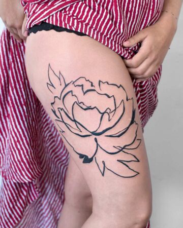 A woman's thigh displays a large black line art peony tattoo. She wears a red and white striped dress, revealing the tattoo. The design emphasizes the flower's petals and center.
