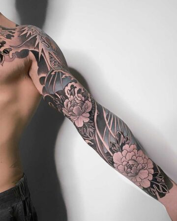 Detailed black and grey Japanese tattoo sleeve featuring peonies and a dragon on a man's arm. The floral design contrasts with the dragon imagery, showcasing traditional tattoo art. Japanese (Irezumi/Wabori) tattoo artist studio Canggu Bali