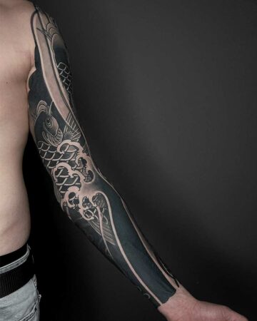 Detailed blackwork tattoo sleeve featuring a koi fish and water waves, covering a man's entire arm from shoulder to wrist. Japanese (Irezumi/Wabori) tattoo studio Canggu Bali