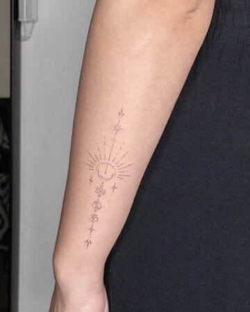Fine line tattoo on a forearm featuring celestial symbols: a crescent moon with radiating lines, stars, an endless knot, and the Om symbol, creating a spiritual and minimalist design.