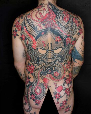 Full back tattoo featuring a traditional Japanese Hannya mask entwined with a snake and cherry blossoms. The mask is grey with red accents, the snake is red and grey, and the blossoms are red with dark centers. Japanese (Irezumi/Wabori) tattoo artist studio Canggu Bali