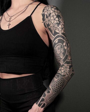 Woman's arm featuring a detailed Japanese-style tattoo sleeve with koi fish and cherry blossoms in black and gray ink. Japanese (Irezumi/Wabori) tattoo artist studio Canggu Bali