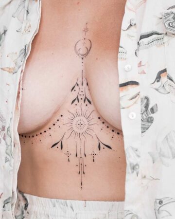 A delicate fine-line sternum tattoo featuring a central sunburst with radiating lines, celestial moon phases, and dainty dot work extending under the bust.