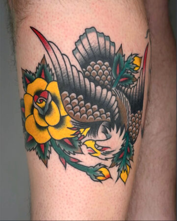 A vibrant color traditional tattoo of a fierce eagle in flight, clutching a bright yellow rose with green leaves. Created in a multi style tattoo studio in Canggu Bali.