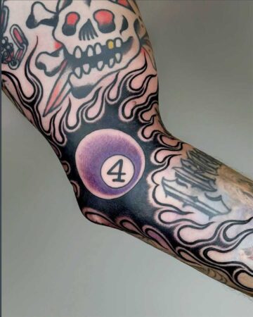 Vibrant color traditional tattoo of a skull with flames and a purple 8-ball with the number 4, showcasing bold lines and shading. Created in the multi style tattoo studio in Canggu Bali, Bali tattoo artist, best tattoo studio Bali.