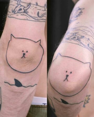 Close-up of a person's arm featuring a minimalist cat tattoo on the elbow, resembling a simple outline drawing. Bali tattoo design. Created by the best tattoo artists in Canggu Bali.