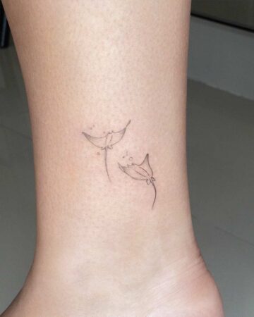 Delicate fine-line marine life tattoo of two stingrays on an ankle. A subtle and elegant aquatic creature design.