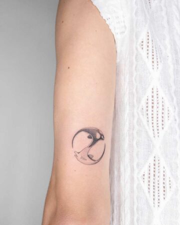 A marine life tattoo featuring an orca and a dolphin in a yin-yang design on an arm. This aquatic creature tattoo showcases a balance of sea life.