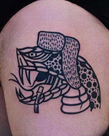 Close-up of a unique SNAKE TATTOO featuring a snake head with bared fangs and a cigarette, adorned with a fur hat. Created by the best tattoo artists in Canggu Bali for your Bali tattoo needs.