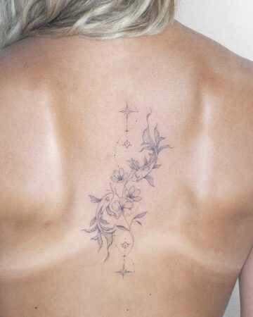 Elegant back tattoo featuring two koi fish swimming amidst delicate cherry blossoms, connected by a trail of stars. A beautiful example of aquatic creatures tattoo art. Created by our tattoo artists in Canggu, Bali