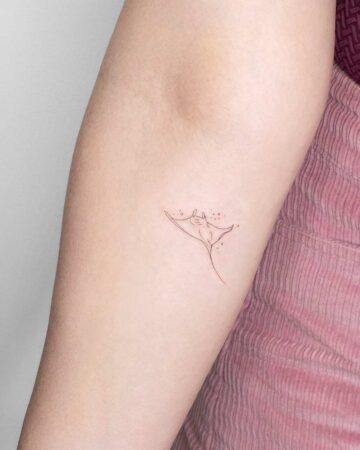 A delicate, minimalist line art marine life tattoo of a manta ray on a person's inner arm. The simple design captures the ray's graceful form.