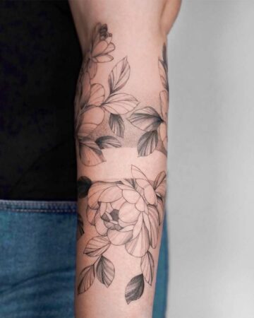 Elegant peony tattoo wrapping around a forearm, featuring delicate linework and subtle shading. A beautiful floral design from a peony tattoo gallery.