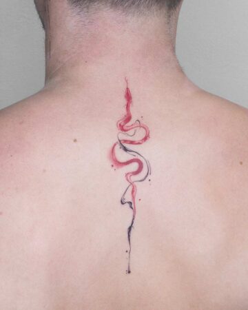 A minimalist snake tattoo design in red and black ink, vertically centered on a person's upper back. This striking SNAKE TATTOO features an abstract, watercolor style. Created by our tattoo artists in Canggu, Bali