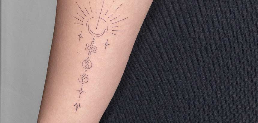 Fine line tattoo on a forearm featuring celestial symbols: a crescent moon with radiating lines, stars, an endless knot, and the Om symbol, creating a spiritual and minimalist design.