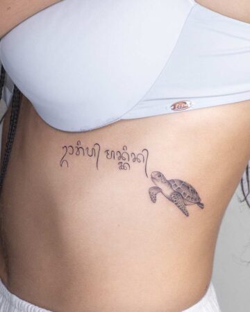 Ribcage tattoo featuring a sea turtle and elegant script, part of an aquatic creatures tattoo gallery. The delicate linework and placement make it a striking piece of marine life body art. Created by our tattoo artists in Canggu, Bali