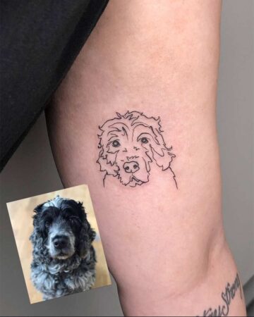A minimalist line art dog tattoo, a portrait of a curly-haired dog, is displayed on an arm next to the photo reference. A cool dog tattoo idea. Created by tattoo artists in Canggu Bali for your next Bali tattoo.