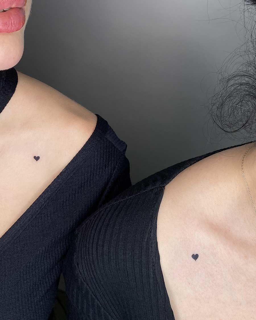 Two friends with matching heart tattoos on their collarbones. A simple and sweet matching tattoo idea. Created by the best expert tattoo artists in Canggu Bali for heart tattoos.
