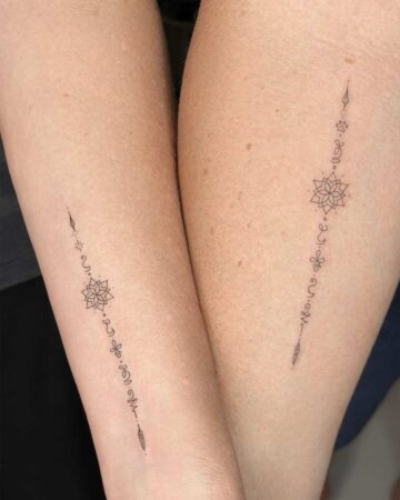 Matching tattoos on two arms, featuring a vertical line of delicate geometric and floral designs. A beautiful example of couples tattoos. Created by expert tattoo artists in Bali.