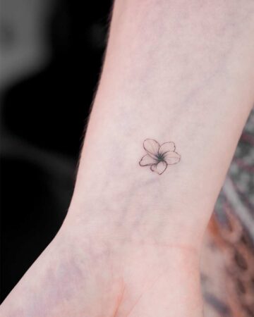 Delicate frangipani tattoo on a fair wrist. A minimalist floral design showcases the simple beauty of the Frangipani. Created by the best tattoo artists in Canggu Bali.