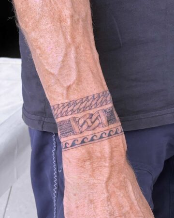 Close-up of a wrist with a bracelet tattoo featuring intricate chain and wave designs. A unique body art piece. Created by expert tattoo artists in Canggu Bali for stunning bracelet tattoos.