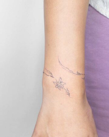 Close-up of a delicate bracelet tattoo featuring a floral design encircling a wrist. A minimalist, fine-line tattoo aesthetic. Created by the best expert tattoo artists in Canggu Bali.