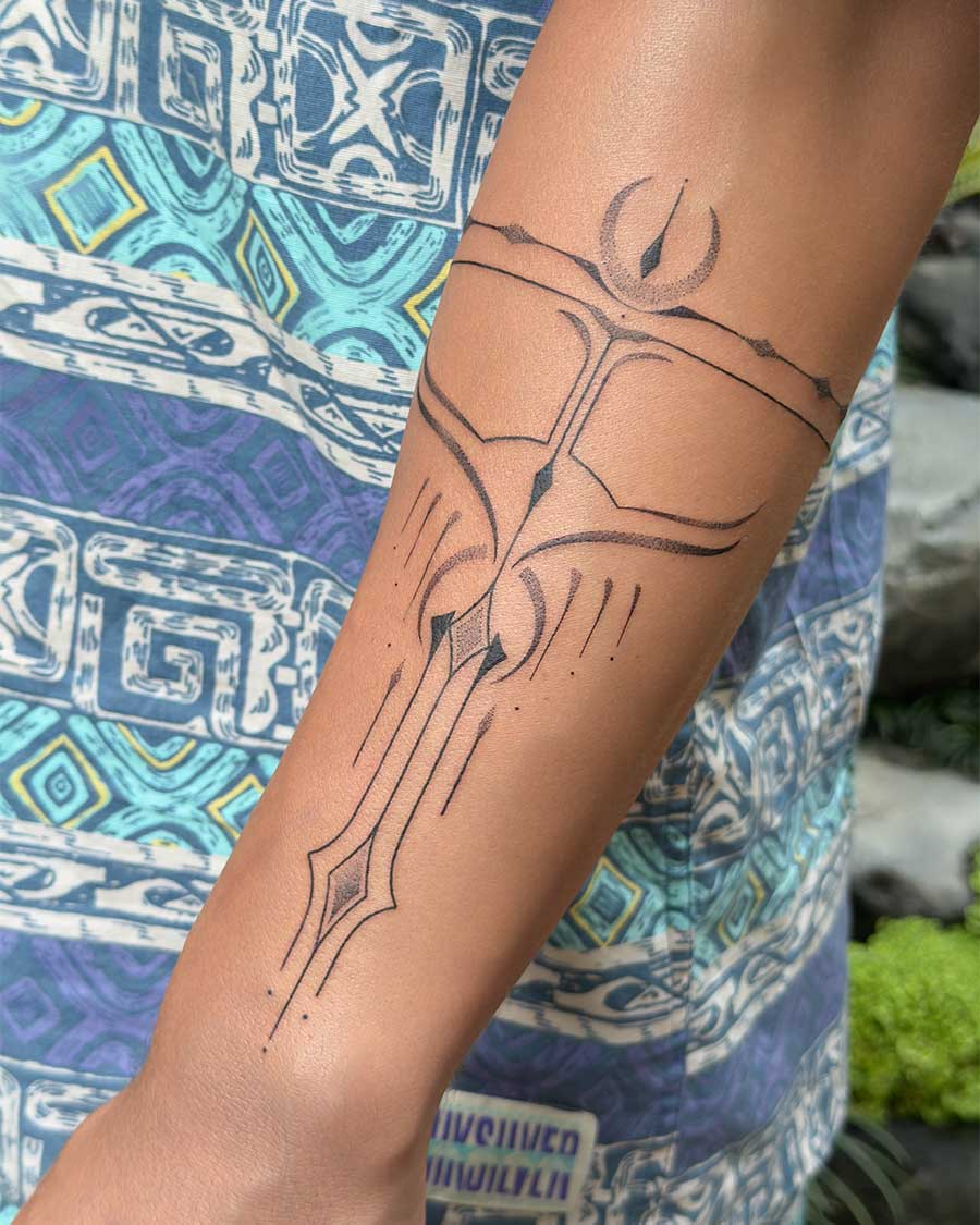 Close-up of an ornamental tattoo on an arm, featuring intricate geometric lines and abstract shapes resembling a stylized sword and celestial elements. This ornamental tattoo showcases fine-line artistry. Created in the multi style tattoo studio in Canggu Bali, Bali tattoo artist.